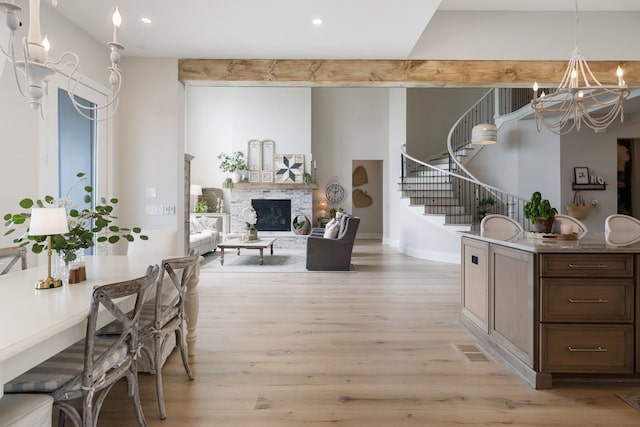 dining space with an inviting chandelier, light hardwood / wood-style floors, and a stone fireplace