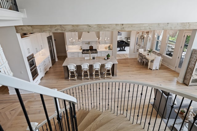 staircase with sink, an inviting chandelier, and hardwood / wood-style flooring