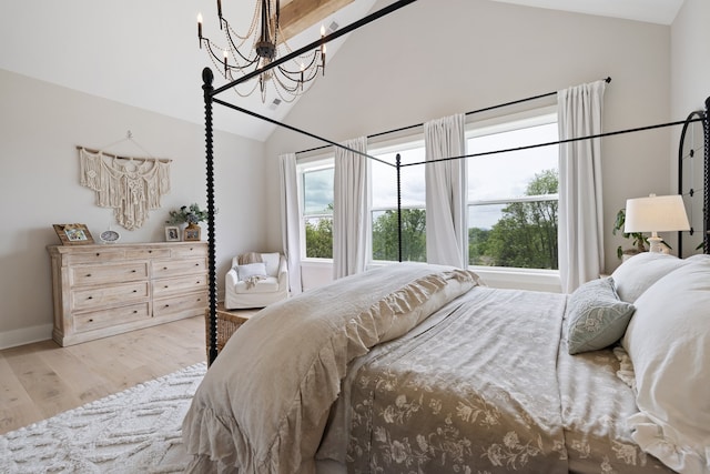 bedroom featuring a notable chandelier, light wood-type flooring, and lofted ceiling