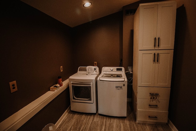 washroom featuring cabinets, separate washer and dryer, and light hardwood / wood-style flooring