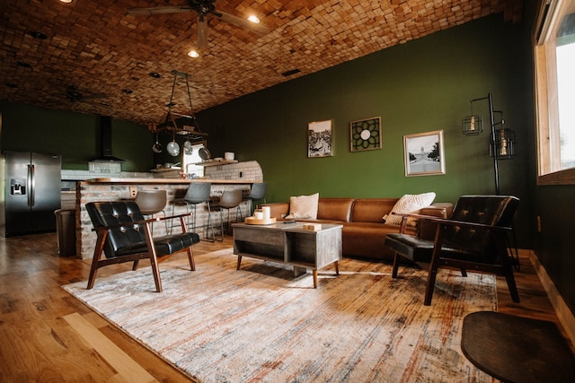 interior space with ceiling fan, light wood-type flooring, brick ceiling, and vaulted ceiling