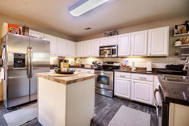 kitchen with dark wood-type flooring, sink, a kitchen island, white cabinetry, and stainless steel appliances