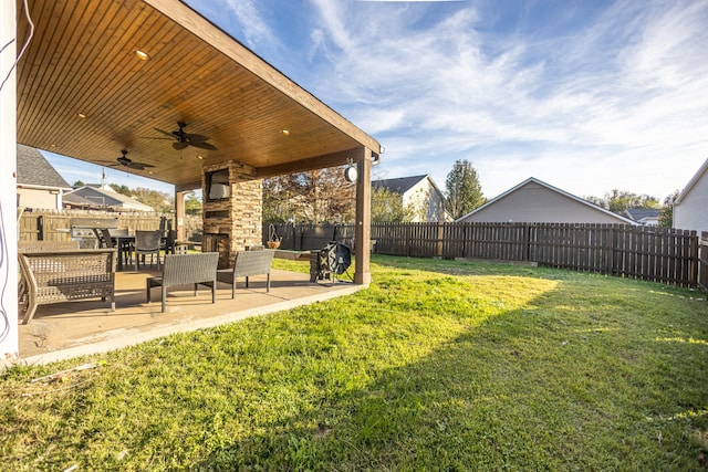 view of yard with an outdoor stone fireplace, ceiling fan, and a patio