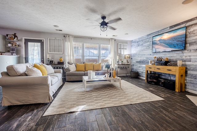 living room featuring a textured ceiling, dark hardwood / wood-style floors, ceiling fan, and wooden walls