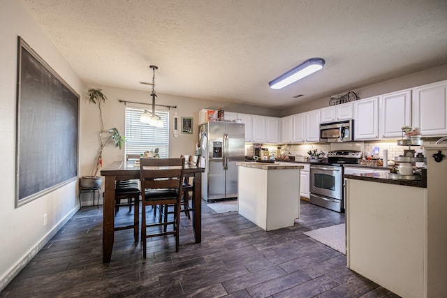 kitchen featuring a center island, hanging light fixtures, dark hardwood / wood-style flooring, white cabinets, and appliances with stainless steel finishes