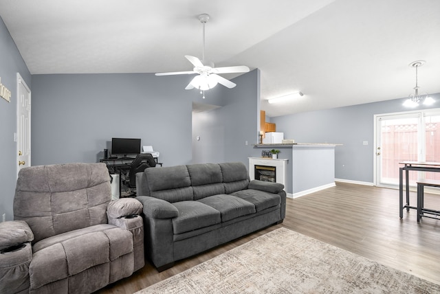 living room featuring hardwood / wood-style flooring, ceiling fan with notable chandelier, and vaulted ceiling