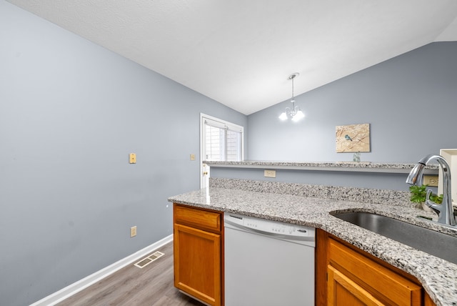 kitchen with pendant lighting, lofted ceiling, white dishwasher, sink, and light hardwood / wood-style floors