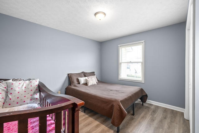 bedroom featuring a textured ceiling and light hardwood / wood-style flooring