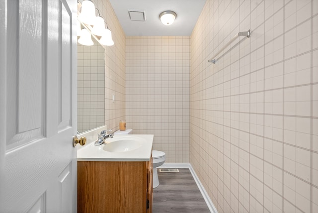 bathroom featuring hardwood / wood-style floors, vanity, toilet, and tile walls