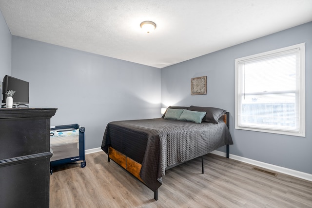 bedroom featuring a textured ceiling and light hardwood / wood-style floors