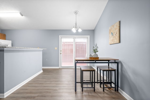 dining room featuring lofted ceiling, hardwood / wood-style flooring, and a notable chandelier