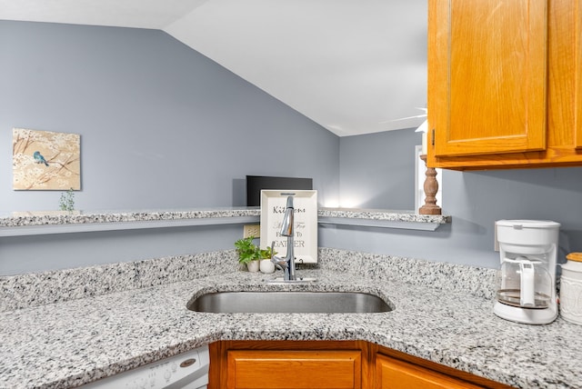 kitchen featuring light stone counters, sink, white dishwasher, and lofted ceiling