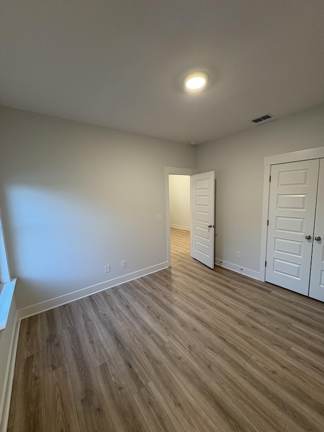 unfurnished bedroom with light hardwood / wood-style flooring and a closet