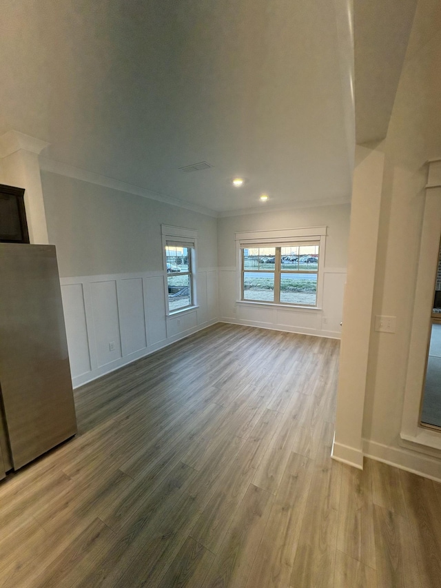 unfurnished living room featuring hardwood / wood-style floors and crown molding