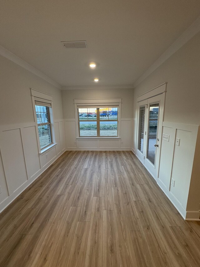 empty room with light hardwood / wood-style floors and crown molding