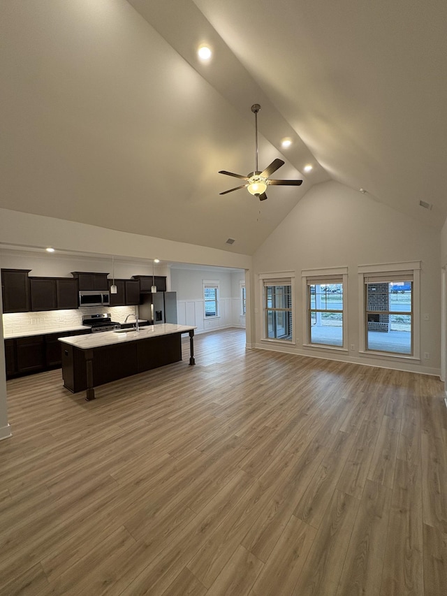 unfurnished living room featuring ceiling fan, sink, high vaulted ceiling, and hardwood / wood-style floors