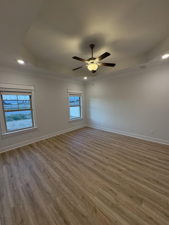 unfurnished room featuring ornamental molding, a tray ceiling, ceiling fan, and light hardwood / wood-style floors