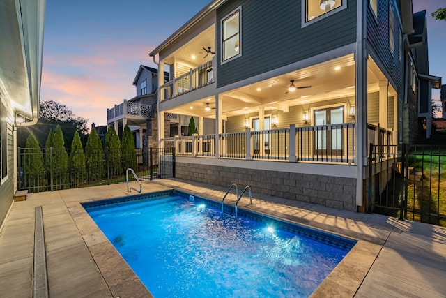 pool at dusk with a patio area and ceiling fan