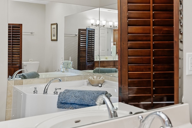 bathroom featuring a tub to relax in, an inviting chandelier, and toilet