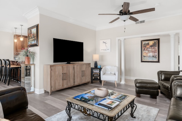 living room featuring light wood-type flooring, ornate columns, ceiling fan, and crown molding