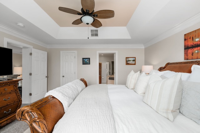 bedroom featuring ceiling fan, crown molding, ensuite bathroom, and a tray ceiling