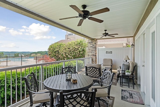 view of patio with ceiling fan, a water view, and a balcony