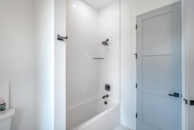 bathroom with toilet and tiled shower / bath