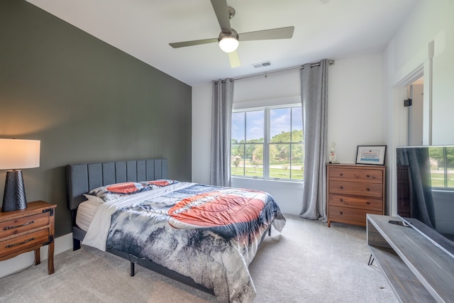 bedroom with multiple windows, ceiling fan, and light colored carpet