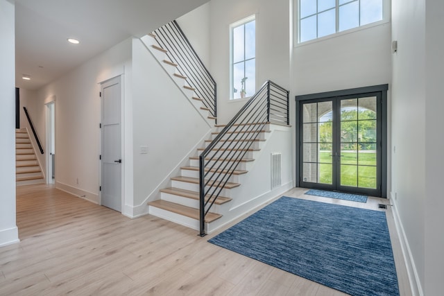 entrance foyer with french doors, light wood-type flooring, and a high ceiling