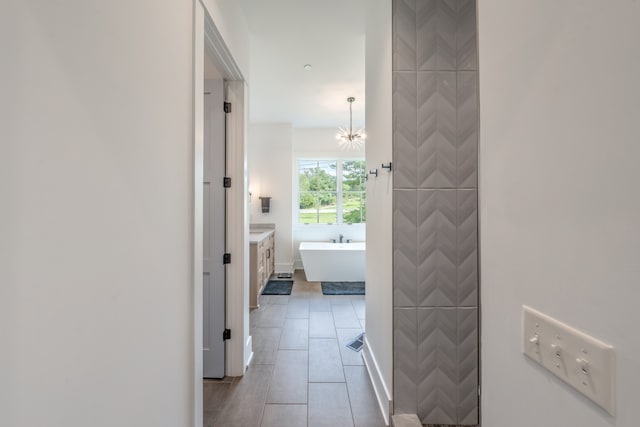 corridor with light tile patterned floors and an inviting chandelier