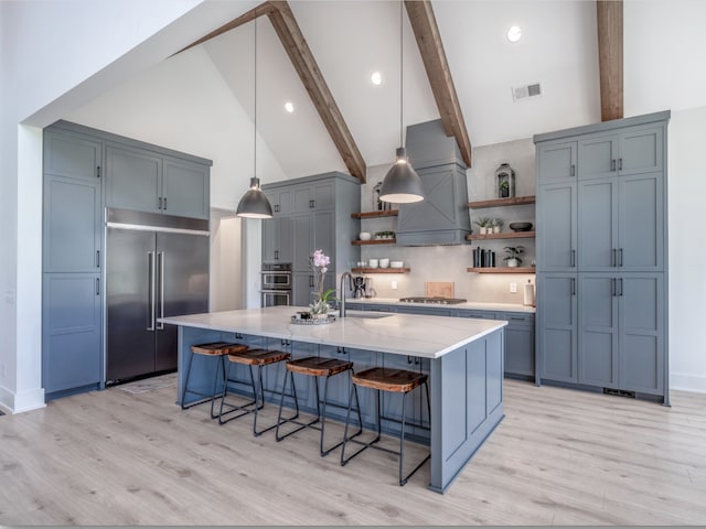 kitchen with appliances with stainless steel finishes, sink, light hardwood / wood-style flooring, high vaulted ceiling, and beamed ceiling