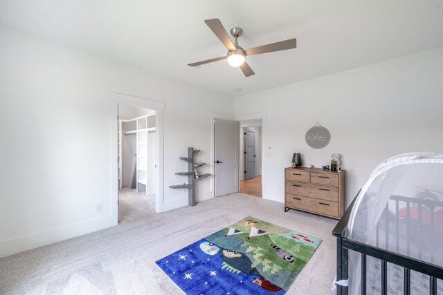 carpeted bedroom featuring ceiling fan and a spacious closet