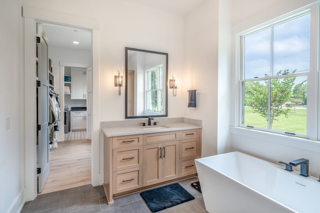 bathroom with a tub to relax in, hardwood / wood-style floors, and vanity