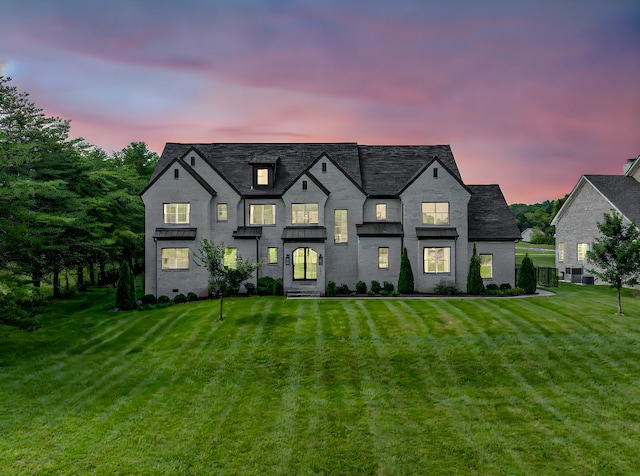 back house at dusk featuring a yard