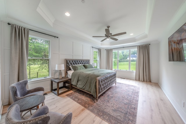 bedroom with ceiling fan, light wood-type flooring, crown molding, and a tray ceiling