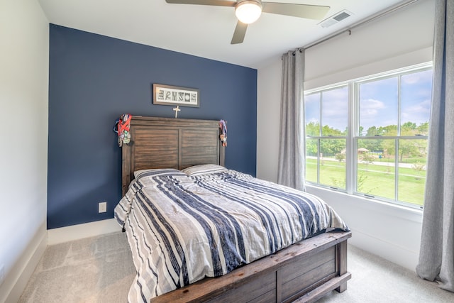 bedroom with light carpet, multiple windows, and ceiling fan