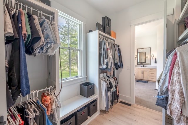 walk in closet with light hardwood / wood-style floors