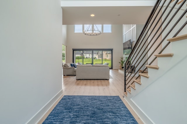 entrance foyer featuring a notable chandelier, a towering ceiling, and light hardwood / wood-style flooring