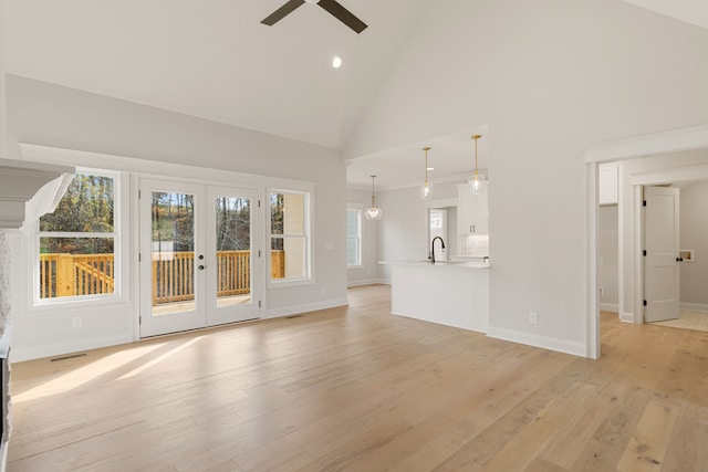 unfurnished living room with ceiling fan, french doors, sink, high vaulted ceiling, and light hardwood / wood-style floors