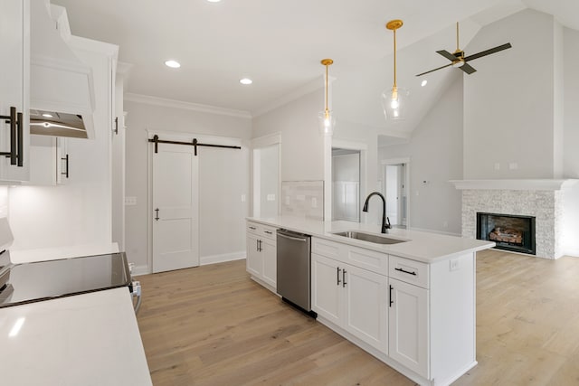 kitchen featuring lofted ceiling, sink, stainless steel dishwasher, a barn door, and white cabinetry