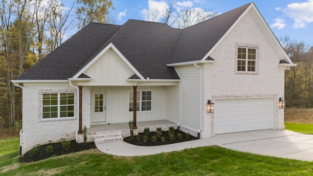 view of front of home featuring covered porch, a garage, and a front yard