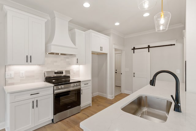 kitchen featuring white cabinets, sink, hanging light fixtures, a barn door, and stainless steel range oven