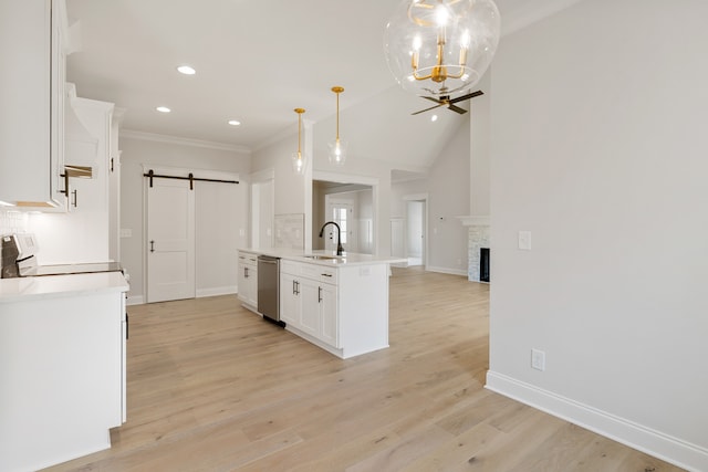 kitchen featuring dishwasher, sink, hanging light fixtures, a barn door, and white cabinetry