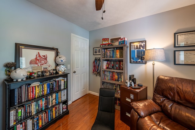 living area with ceiling fan, hardwood / wood-style floors, and a textured ceiling