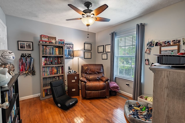 sitting room with wood-type flooring, a textured ceiling, and ceiling fan