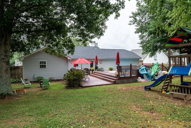 back of property with a playground, a deck, and a yard