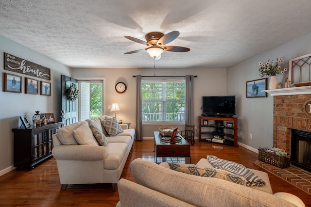 living room featuring a textured ceiling, a fireplace, ceiling fan, and dark wood-type flooring