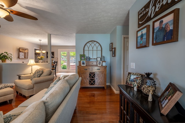 living room featuring hardwood / wood-style floors, ceiling fan with notable chandelier, and a textured ceiling