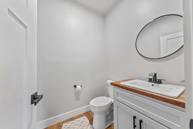 bathroom with toilet, vanity, and hardwood / wood-style flooring