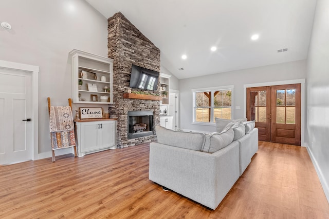 living room with high vaulted ceiling, french doors, a fireplace, and light hardwood / wood-style flooring